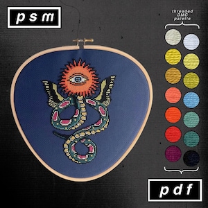 May include: Cross-stitch embroidery in a wooden hoop featuring a colorful design of an eye within a sunburst, a snake, and butterfly wings on a navy blue background. The text "psm" and "pdf" are in white boxes. A color palette is shown.
