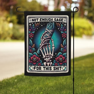May include: Black garden flag with the text "NOT ENOUGH SAGE FOR THIS SHIT" and a skeleton hand holding a bundle of sage. The design includes red roses, teal accents, and a teal background.