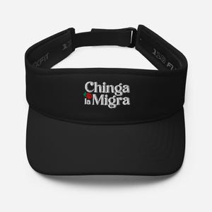 Può includere: Visiera nera con la scritta ricamata "Chinga la Migra" in bianco, con un accento di rosa rossa. La visiera ha una visiera curva e un cinturino regolabile. Il marchio "Flexfit" è visibile sul lato.