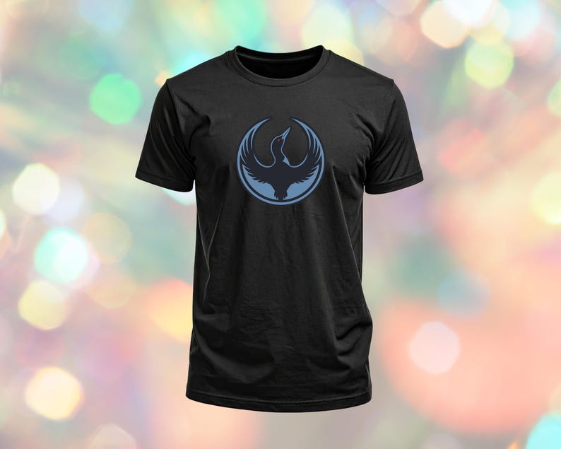 May include: Black t-shirt featuring a blue circular design with a bird emblem. The bird is depicted with outstretched wings inside a circle. The t-shirt is made of a soft material and has short sleeves.