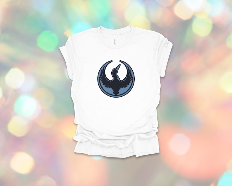 May include: White t-shirt featuring a dark blue bird emblem within a circular frame. The bird design has a stylized, minimalist aesthetic. The shirt is made of a soft material and has a classic crew neck.