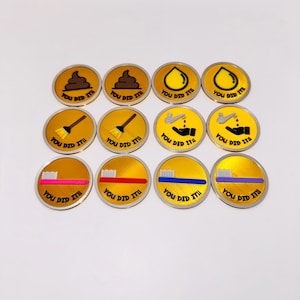May include: A collection of twelve gold-colored circular tokens with various icons and the text "YOU DID IT". The icons include a pile of poop, a water droplet, a broom, a hand washing, and a toothbrush.