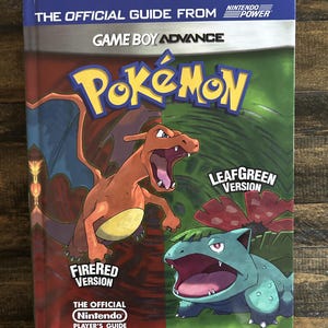 May include: A Game Boy Advance "Pokémon" player's guide. The cover features Charizard and Venusaur, with the text "FireRed Version" and "LeafGreen Version." The guide is published by Nintendo Power.