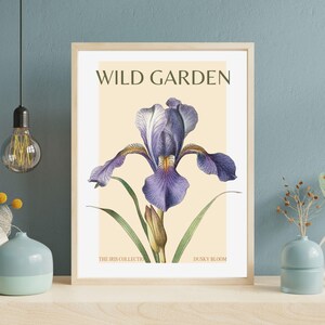Könnte beinhalten: Eine Vintage-botanische Illustration einer violetten Iris-Blume mit grünen Blättern. Das Bild trägt den Titel "WILD GARDEN" und "THE IRIS COLLECTION" und "DUSKY BLOOM".