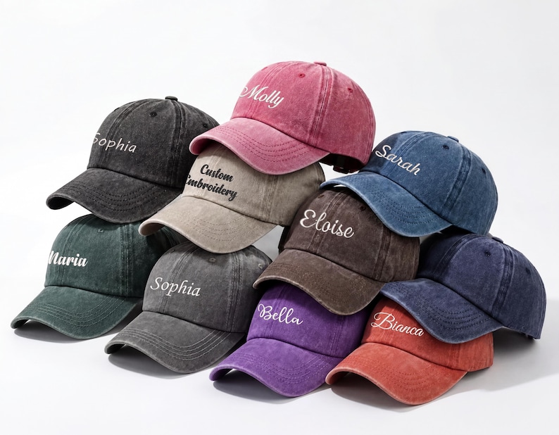 May include: A collection of baseball caps in various colors, including black, green, pink, and blue. Each cap features a curved brim and embroidered text with names like "Sophia" and "Molly". The caps are made of a worn, vintage-style fabric.