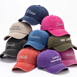 May include: A collection of baseball caps in various colors, including navy, pink, red, and purple. Each cap features embroidered text, such as names and the phrase "Custom Embroidery". The caps are stacked, showcasing their design.