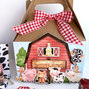 Può includere: Una scatola regalo di cartone marrone con un fiocco a quadretti rossi e bianchi. La scatola presenta una scena di fattoria con un fienile rosso, animali della fattoria e la scritta "Samuel's Farm". È visibile anche il numero "2".