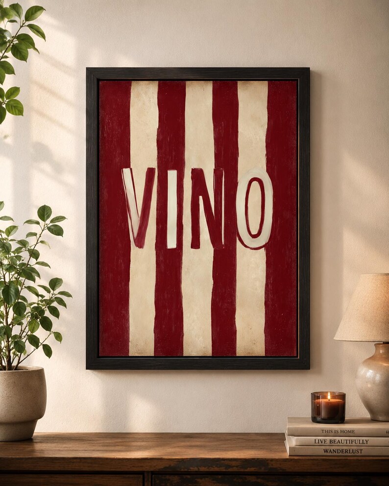 Op de afbeelding: Zwart omlijst kunstwerk met rode en cr&egrave;mekleurige verticale strepen en het woord "VINO" in witte letters. Het kunstwerk hangt aan de muur boven een houten oppervlak.