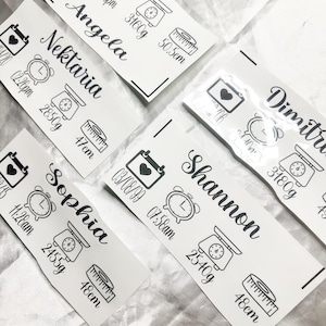 May include: White rectangular stickers with black text and illustrations. Each sticker displays a name, date, time, weight in grams, and length in centimetres. The stickers include icons of a calendar, clock, scale, and measuring tape.