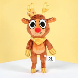 May include: A plush reindeer toy with a brown body, large white-rimmed eyes, and a red nose. It has yellow antlers, a yellow scarf, and yellow striped accents on its legs and arms. A white tag with black text is attached to the toy.