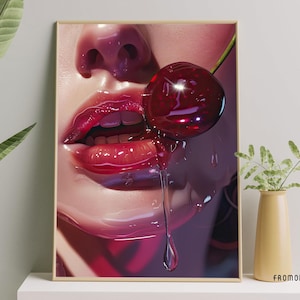 May include: A framed print showing a close-up of a face with glossy red lips and a cherry. The cherry drips juice, creating a sensual image. The artwork has a vibrant, glossy finish, with a focus on the details.
