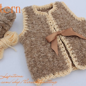 May include: A brown crocheted waistcoat with a cream coloured trim and a brown satin ribbon tied at the front. The waistcoat is made with a fluffy yarn. The yarn for the waistcoat is shown in the image.