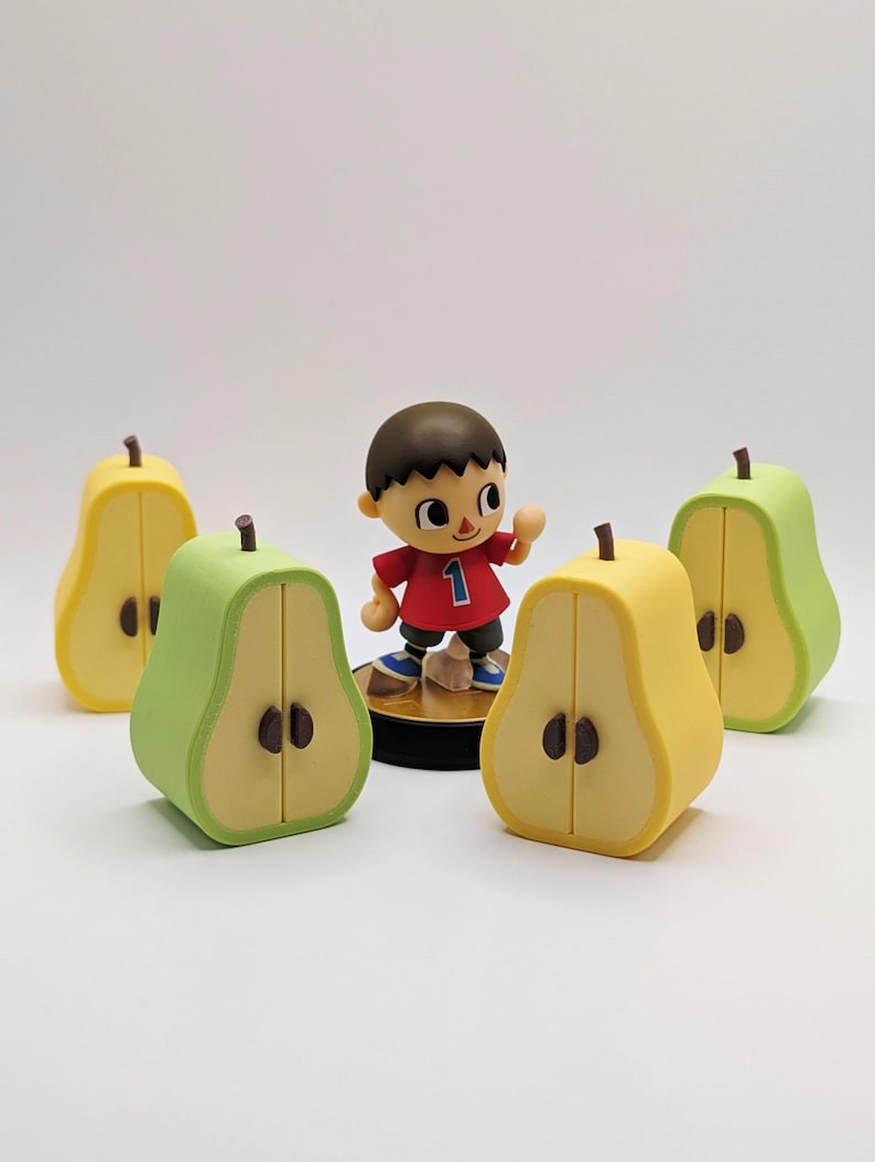 Puede incluir: Una figura de un personaje del videojuego Animal Crossing, con una camisa roja con el n&uacute;mero 1. Cuatro recipientes en forma de pera en amarillo y verde rodean la figura. Las peras tienen semillas y tallos marrones.