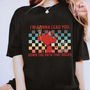May include: Black graphic t-shirt featuring a red devil character with a trident, set against a checkered background. The text reads "I'M GONNA LEAD YOU DOWN THE PATH THAT ROCKS."