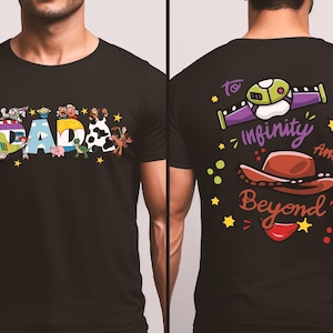 Puede incluir: Camiseta negra con la palabra "DAD" en letras coloridas y personajes de dibujos animados. La parte trasera de la camiseta tiene la frase "To infinity and beyond" con un sombrero de vaquero y un dise&ntilde;o de nave espacial.