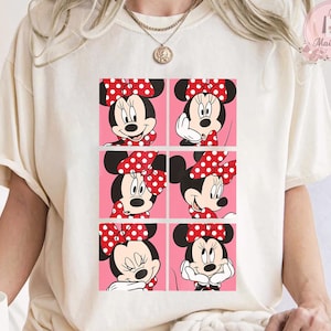 Puede incluir: Camiseta color crema con un dise&ntilde;o gr&aacute;fico de seis paneles de Minnie Mouse en varias poses. Cada panel muestra la cara de Minnie con su lazo rojo caracter&iacute;stico con lunares blancos sobre un fondo rosa. La camiseta tiene cuello redondo y mangas cortas.