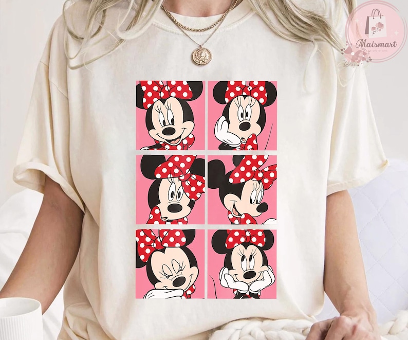 Puede incluir: Camiseta color crema con un dise&ntilde;o gr&aacute;fico de seis paneles de Minnie Mouse en varias poses. Cada panel muestra la cara de Minnie con su lazo rojo caracter&iacute;stico con lunares blancos sobre un fondo rosa. La camiseta tiene cuello redondo y mangas cortas.