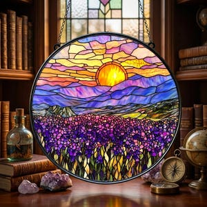 May include: A round stained glass window depicting a sunset over a field of purple flowers and mountains. The sun is a bright yellow, and the sky is a mix of orange, pink, and blue. The window is framed in black and hangs from a chain.