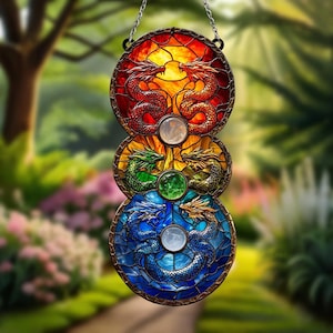 May include: A vertical stained glass suncatcher featuring three circular sections with dragon motifs. The top section is red and orange, the middle is yellow and green, and the bottom is blue. Each section contains a central circular gemstone.