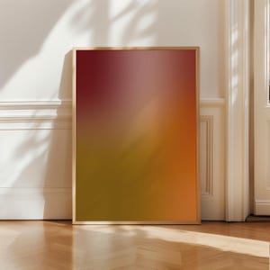 May include: A framed art print with a gradient design. The colors transition from deep red at the top to a golden yellow at the bottom, with shades of orange and pink in between. The frame is a light wood color.