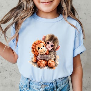 May include: A light blue t-shirt featuring a watercolor illustration of two hugging monkeys. One monkey is brown and the other is orange. The shirt is made of a soft material and is suitable for children.