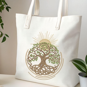 May include: Cream-coloured tote bag with a detailed tree illustration, featuring intertwined roots, green leaves, and a sunburst design. The bag has long, cream-coloured handles and is made of a textured material. The design is centred.