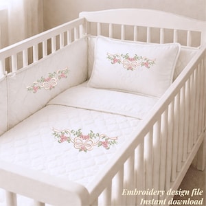 以下が含まれることがあります： 白いベビーベッドと、花柄とリボンの刺繍が施された寝具。 セットには、キルティングバンパー、枕、毛布が含まれており、すべてピンクのバラと緑の葉で飾られています。 テキスト「Embroidery design file Instant download」が表示されます。
