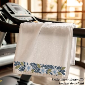 May include: A white towel with an embroidered floral border featuring blue and green leaves and light blue flowers. The towel is draped over a treadmill handle. The text "Embroidery design file Instant download" is at the bottom.