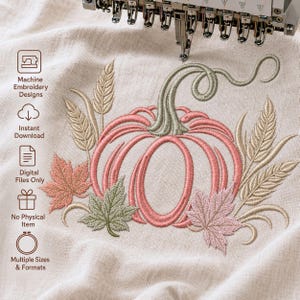 Op de afbeelding: Een borduurontwerp op lichtbeige stof met een centrale roze pompoen met een saliegroene steel, omringd door tarwearen en esdoornbladeren in tinten roze, groen en beige. De tekst aan de linkerkant luidt Machine Embroidery Designs.