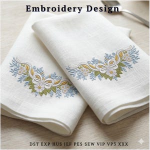 May include: Two white linen napkins with embroidered floral designs. The embroidery features white flowers, green leaves, and blue accents, with a yellow ribbon detail. The text "Embroidery Design" is at the top.