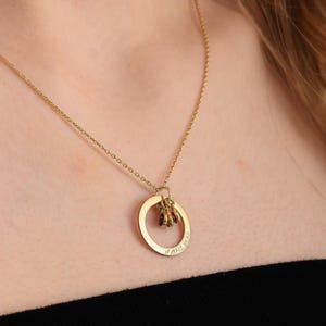 May include: A gold chain necklace with a circular pendant that has the words "I love you" engraved on it. The pendant has three small purple gemstones attached to it.