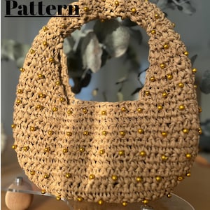 May include: A beige crochet handbag with a rounded shape and a circular handle. The bag is adorned with small, gold-colored beads. The words "Crochet Pattern" are displayed in black text at the top of the image.