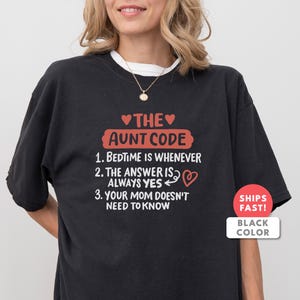 Könnte beinhalten: Schwarzes T-Shirt mit dem Text "THE AUNT CODE" in Rot und Weiß. Der Text enthält die Sätze "BEDTIME IS WHENEVER", "THE ANSWER IS ALWAYS YES" und "YOUR MOM DOESN'T NEED TO KNOW".
