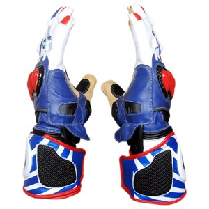 May include: Pair of motorcycle gloves in white, blue, red, and black. The gloves have a leather exterior with protective padding on the knuckles and wrist. The design includes a blue and white striped pattern on the wrist area.