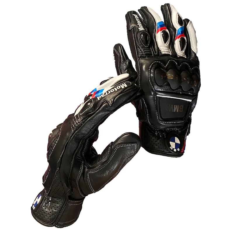 K&ouml;nnte beinhalten: Schwarze Motorradhandschuhe aus Leder mit wei&szlig;en, blauen und roten Akzenten. Die Handschuhe zeigen die Logos "Motorrad" und "BMW". Sie verf&uuml;gen &uuml;ber Kn&ouml;chelschutz und sind zur Bel&uuml;ftung perforiert.