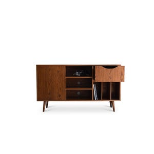 Op de afbeelding: Een houten kast in mid-century modern stijl met een warme bruine afwerking. Het heeft een deur, lades en open vakken voor opslag. De kast heeft taps toelopende poten en een gedeeltelijk open lade, die de binnenkant laat zien.