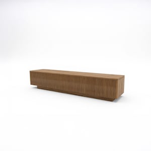 May include: A long, rectangular wooden media console with a light brown finish. The front features vertical, ridged detailing. The console sits on a low, solid base, and is suitable for a living room or entertainment space.