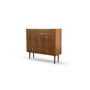 Op de afbeelding: Een dressoir in mid-century stijl met acht lades en een houten afwerking. De commode heeft messing knoppen en taps toelopende poten. De houtnerf is zichtbaar. Het geheel staat tegen een witte achtergrond.