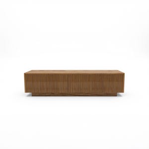 May include: A rectangular wooden coffee table with a light brown finish. The table features vertical grooved detailing across the front and sides, and sits on a low, solid base. The design is modern and minimalist.