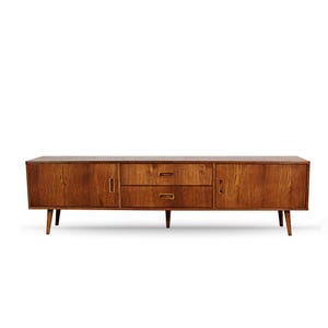 Könnte beinhalten: Ein Sideboard aus Holz im Mid-Century-Modern-Stil mit warmbraunem Finish. Es hat zwei Türen, zwei Schubladen und konische Beine. Die Türen und Schubladen haben einfache, eingelassene Griffe. Ca. 180 cm lang.