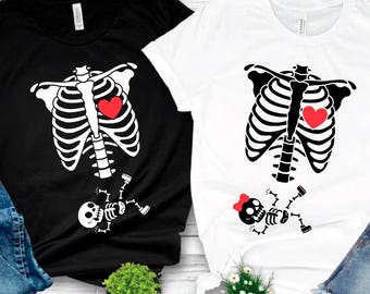 Könnte beinhalten: Zwei T-Shirts, eines in Schwarz und eines in Weiß, jeweils mit einem Skelett-Brustkorb-Design und einem roten Herzen. Das schwarze Shirt hat ein Skelett-Baby-Design. Das weiße Shirt hat ein Skelett-Baby mit einer roten Schleife. Der untere Teil des Bildes enthält die Wörter "SVG PDF EPS DXF PNG".