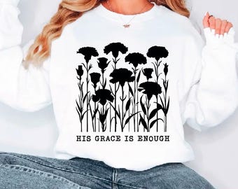 May include: White sweatshirt featuring a black floral design with the text "HIS GRACE IS ENOUGH". The graphic includes stylized flowers and stems. The bottom of the image shows file type icons: SVG, PDF, EPS, DXF, and PNG.
