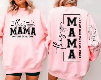 Könnte beinhalten: Ein hellrosa Sweatshirt mit dem Text "this MAMA loves her spooky crew" in Schwarz. Auf der Rückseite des Sweatshirts steht das Wort "MAMA" in einem vertikalen Block, mit dem Text "Loves her spooky crew" und zwei Geistergrafiken.