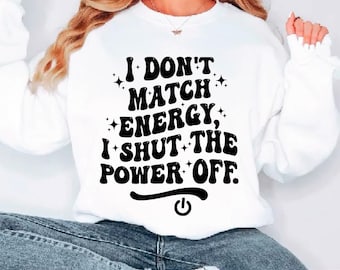 May include: White sweatshirt with the text "I DON'T MATCH ENERGY, I SHUT THE POWER OFF." in black, stylized font. The design includes star accents and a power button symbol. The bottom of the image shows the words "SVG PDF EPS DXF PNG".