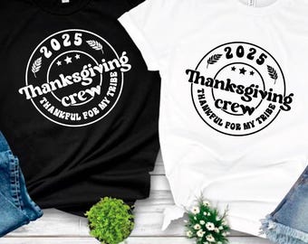以下が含まれることがあります： 「2025 Thanksgiving crew, thankful for my tribe」と書かれた円形グラフィックが特徴の黒と白のTシャツ。デザインには星と麦の穂が含まれています。画像の下部には、ファイルの種類（SVG、PDF、EPS、DXF、PNG）が表示されています。