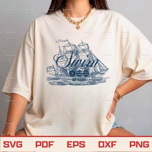 May include: Cream-colored t-shirt featuring a blue illustration of a sailing ship with the word "Swan" in a decorative font. Below the ship, the text reads "1966 ARIRANG". The shirt has short sleeves and a relaxed fit.