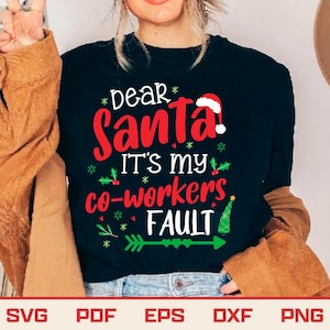 May include: Black crew neck t-shirt with the text "Dear Santa! It's my co-workers FAULT" in red and white. The design includes a Santa hat, holly, and a green arrow. A Christmas-themed graphic tee.
