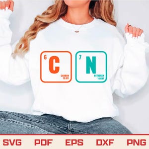 May include: White sweatshirt with the chemical symbols for Carbon and Nitrogen, including atomic numbers and weights. Carbon is in an orange square, Nitrogen in teal. The sweatshirt is worn with blue jeans. The bottom of the image shows SVG, PDF, EPS, DXF, PNG.