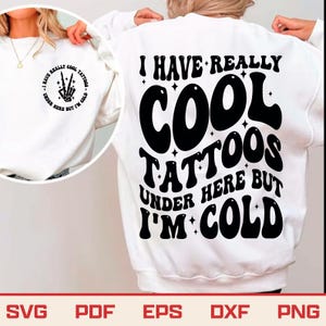 以下が含まれることがあります： 「I HAVE REALLY COOL TATTOOS UNDER HERE BUT I'M COLD」の黒い文字がプリントされた白いスウェットシャツ。スウェットシャツの前面には、同じテキストの小さなデザインがあります。画像の下部には「SVG PDF EPS DXF PNG」というテキストがあります。