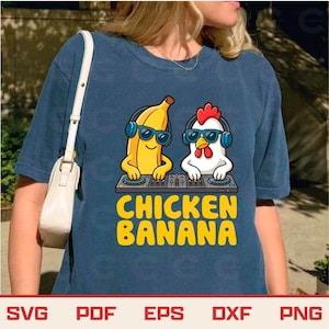 May include: A navy blue t-shirt features a graphic of a banana and a chicken wearing sunglasses and headphones, operating DJ turntables. The text "CHICKEN BANANA" is in yellow block letters below the graphic.